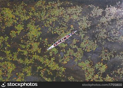Aerial top view of a tourist boat pink lotus flowers in pond or lake in national park in Thale Noi, Songkhla, Thailand.