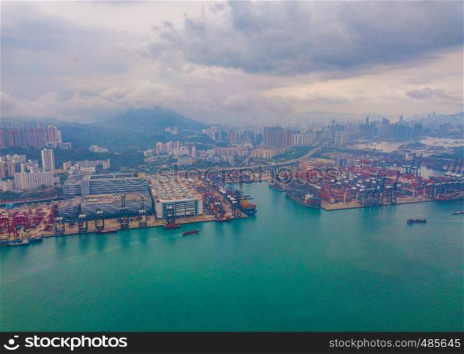 Aerial top view of container cargo ship in the export and import business and logistics international goods in urban city. Shipping to the harbor by crane in Victoria Harbour, Hong Kong.