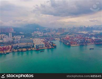 Aerial top view of container cargo ship in the export and import business and logistics international goods in urban city. Shipping to the harbor by crane in Victoria Harbour, Hong Kong.