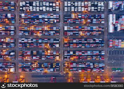 Aerial top view of container cargo ship in the export and import business and logistics international goods in urban city. Shipping to the harbor by crane in Victoria Harbour, Hong Kong City at night.
