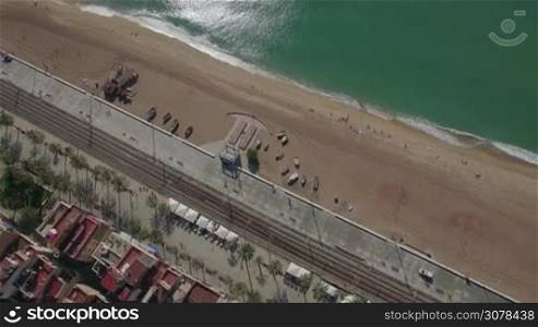 Aerial top view of empty sand beach, blue sea, railways and roofs of hotels, Barcelona, Spain