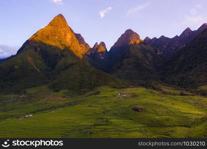 Aerial top view of Fansipan mountains with paddy rice terraces, green agricultural fields in countryside or rural area, hills valley at sunset in Asia, Sapa, Vietnam. Nature landscape background.