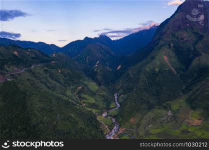 Aerial top view of Fansipan mountains with paddy rice terraces, green agricultural fields in countryside or rural area, hills valley at sunset in Asia, Sapa, Vietnam. Nature landscape background.