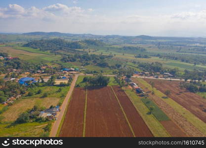 Aerial top view of fresh grass, rice and crops field with green mountain hill in agriculture concept. Nature landscape background in Thailand. harvest