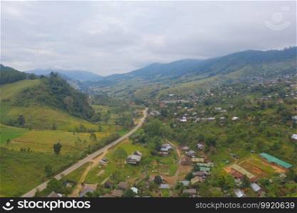 Aerial top view of immigrant refugees residential village houses in countryside, rural area. Local community houses in urban town near natural forest on mountain hills, Tak, Thailand. Evacuation.