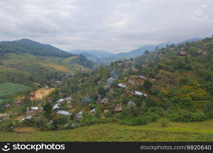 Aerial top view of immigrant refugees residential village houses in countryside, rural area. Local community houses in urban town near natural forest on mountain hills, Tak, Thailand. Evacuation.