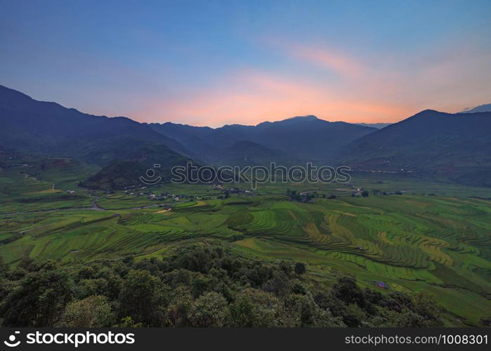 Aerial top view of paddy rice terraces, green agricultural fields in countryside or rural area of Mu Cang Chai, Yen Bai, mountain hills valley at sunset in Asia, Vietnam. Nature landscape background.