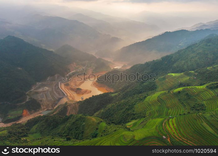 Aerial top view of paddy rice terraces, green agricultural fields in countryside or rural area of Mu Cang Chai, Yen Bai, mountain hills valley at sunset in Asia, Vietnam. Nature landscape background.