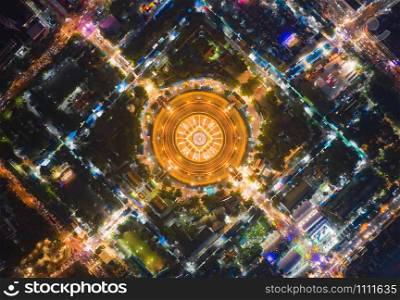 Aerial top view of Phra Pathommachedi temple at night. The golden buddhist pagoda with residential houses, urban city of Nakorn Pathom district, Thailand. Holy Thai architecture.