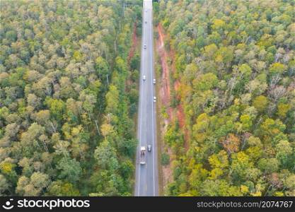 Aerial top view of street road with lush green trees from above in tropical forest in national park and mountain or hill in summer season in Thailand. Natural landscape. Pattern texture background.
