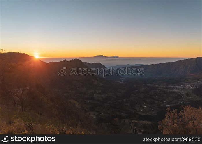 Aerial top view of trees in tropical forest in national park and mountain or hill in summer season in Indonesia at sunset. Natural landscape background.
