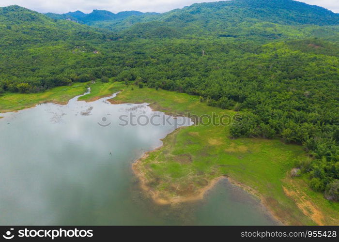 Aerial top view of trees, river or lake in tropical forest in national park and mountain or hill in summer season in Kanchanaburi district, Thailand. Natural landscape background.