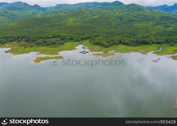 Aerial top view of trees, river or lake in tropical forest in national park and mountain or hill in summer season in Kanchanaburi district, Thailand. Natural landscape background.