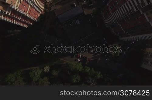 Aerial top view of typical modern sleeping district with residential buildings roofs with yard with trees and trees and playground at summer, Moscow, Russia