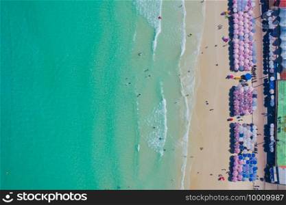 Aerial top view of umbrellas on beach, shore and clear blue turquoise seawater, Andaman sea in summer season. Water in ocean material surface pattern texture wallpaper background.