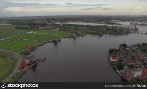 Aerial - Township with old windmills, river with sailing boat and green fields, Netherlands