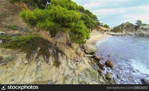 Aerial video shot in a typical Mediterranean beach.Moving along the seashore over Stones, trees and sand with a DJI Phantom quad copter.Calella de Palafrugell beach in Girona, Catalonia.