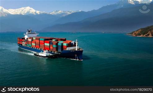 aerial view container cargo ship and tugboat floating carrying commercial container in import export business commerce logistic and transportation of international by container ship open sea mountain background