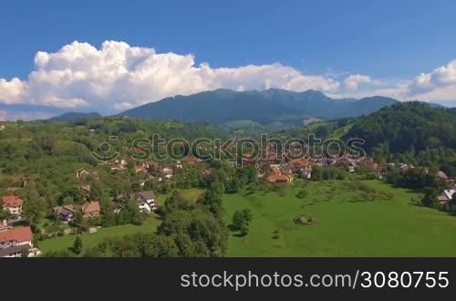Aerial view from above over small village in mountains. Beautiful landscape in summer day.