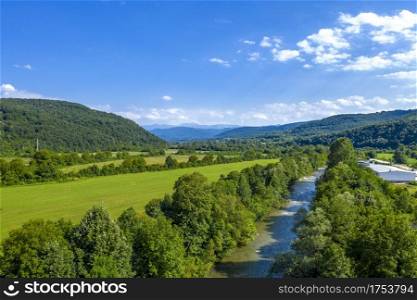 Aerial view from drone of the vast green landscape with river, hills and blue sky