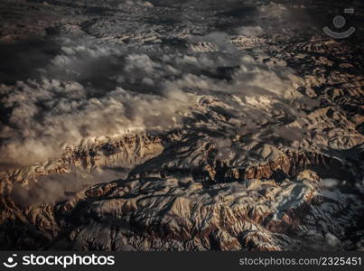 Aerial view from the plane of hills snow and mountains landscape with shadows of sunlight and clouds covered beautifully. Above the clouds, Snow capped mountain, No focus, specifically.