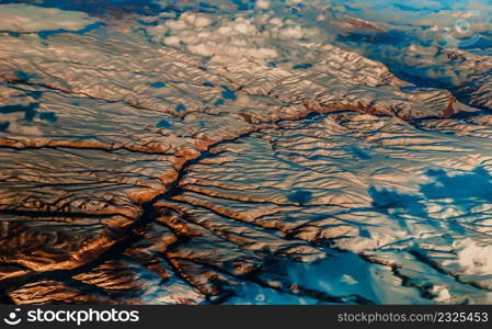 Aerial view from the plane of hills snow and mountains landscape with shadows of sunlight and clouds covered beautifully. Above the clouds, Snow capped mountain, No focus, specifically.