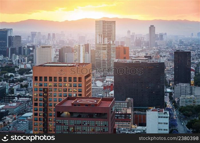 Aerial view from Torre Latinoamericana of Mexico city downtown skyscrapers and mountains at sunset