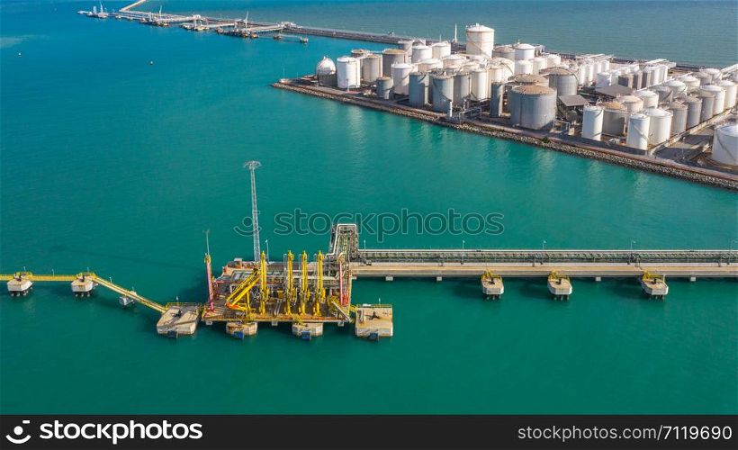 Aerial view loading arm oil and gas refinery at commercial port, Tank terminal with lots of oil storage tank and petrochemical storage tank in the port, Industrial tank storage aerial view.