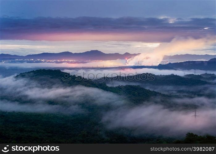 Aerial view mist after the rain on the mountain high voltage pole and steam from a coal power plant at sunset, Pang Puey, Mae Moh, Lampang, Thailand. Energy and environment concept. Long exposure.. Sea of fog and coal power plant.