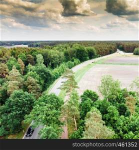 Aerial view of a country road in northern Germany near Celle, with a forest in the foreground and on the left side, fields and meadows right of the road, made with drone