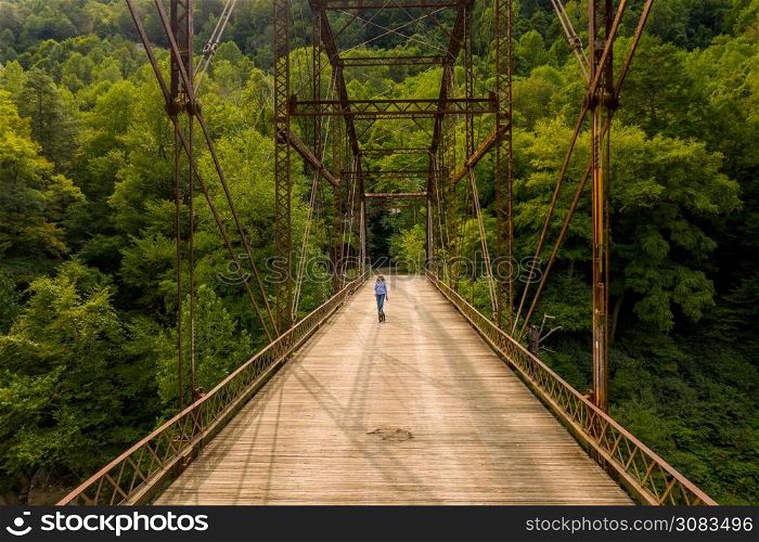 Aerial view of a senior woman walking her dog across the historic metal truss Jenkinsburg Bridge near Morgantown over Cheat River. Drone view of senior woman walking dog across Jenkinsburg Bridge over Cheat River