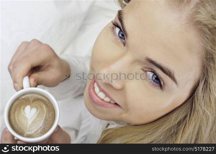 Aerial view of a smiley blonde girl holding a cappuccino