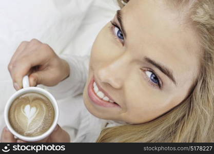 Aerial view of a smiley blonde girl holding a cappuccino