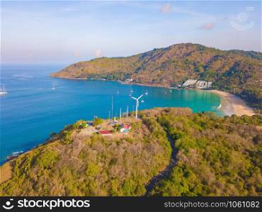 Aerial view of a wind turbine at Patong beach with blue turquoise seawater, and tropical green forest trees with Andaman sea in Phuket island in summer, Thailand in travel trip. Nature background.