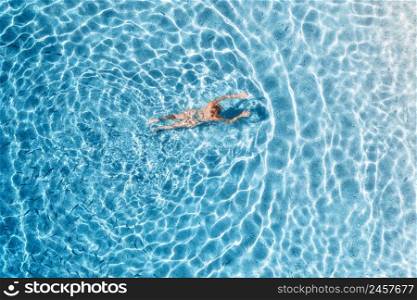 Aerial view of a young woman is swimming in blue sea with school of fish at sunset in summer. Tropical landscape with slim girl, clear water, sandy beach in Lefkada island, Greece. Top view. Travel