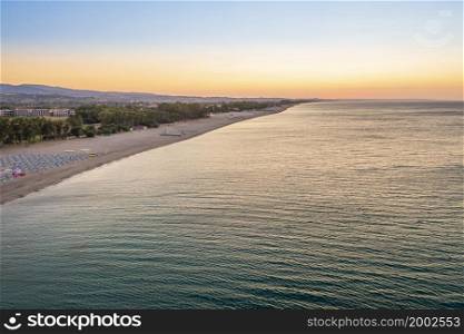 Aerial view of adriatic sea and sandy beach at sunrise, seascape and hill mountain on background, Simeri Mare, Calabria, Southern Italy