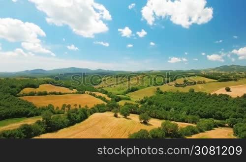Aerial view of agricultural fields by summer cloudy day in Italy, Tuscany. In the background beautiful scenic nature