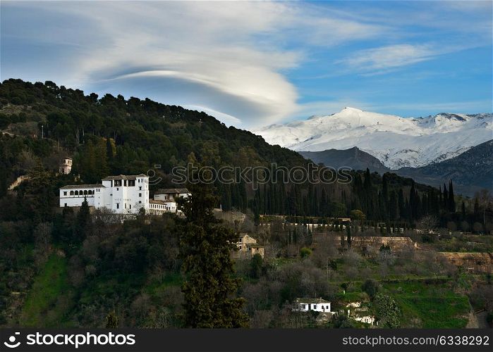 Aerial view of Alhambra and snowing Sierra Nevada mountains under a lenticular cloud