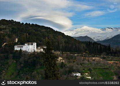 Aerial view of Alhambra and snowing Sierra Nevada mountains under a lenticular cloud