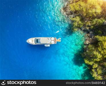 Aerial view of alone beautiful yacht on the sea bay at sunset in summer. Fethiye lagoons, Turkey. Top view of luxury boat, clear blue water, sand, stones and green trees. Tropical landscape. Exotic