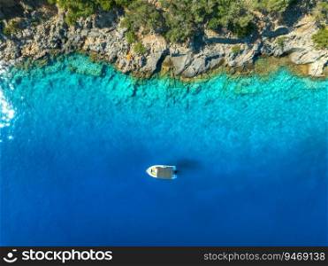 Aerial view of alone small motorboat on the sea in summer sunny day. Oludeniz, Turkey. Top drone view of bay, yacht, sailboats, transparent blue water, sand, stones and green forest. Travel. Boat