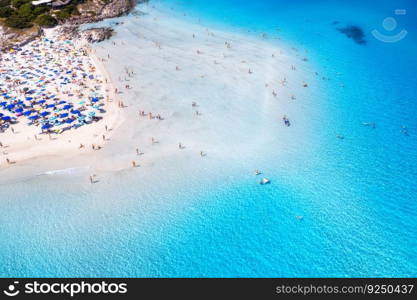 Aerial view of amazing sea coast. Top view from drone of beach with white sand, umbrellas, swimming people in blue transparent water at sunny day. Summer in La Pelosa beach, Sardinia, Italy. Tropical