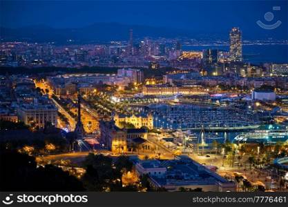 Aerial view of Barcelona city skyline with city traffic and port with yachts illuminated in the night. Barcelona, Spain. Aerial view of Barcelona city and port with yachts