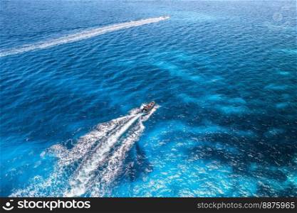Aerial view of beautiful floating speed boat in blue sea at sunny day in summer. Sardinia island, Italy. Top view of yacht,  turquoise transparent water. Travel. Tropical seascape. Motorboat 