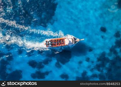 Aerial view of beautiful floating yacht in blue sea at sunny day in summer. Sardinia island, Italy. Drone view of speed boat, sea coast, transparent water. Travel. Tropical landscape. Yachting 