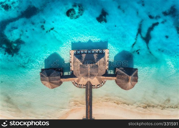 Aerial view of beautiful hotel in Indian ocean at sunrise in summer. Zanzibar, Africa. Top view. Building on the sea. Aerial landscape with wooden hotel, clear azure water, sandy beach. Luxury resort