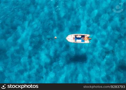 Aerial view of beautiful little boat in blue sea at sunset in summer. Sardinia, Italy. Top drone view of motorboat, ocean with transparent azure water. Travel. Tropical landscape. Yachting. Seascape
