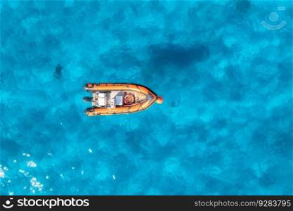 Aerial view of beautiful orange boat in blue sea at sunset in summer. Sardinia, Italy. Top drone view of motorboat, ocean with transparent azure water. Travel. Tropical landscape. Yachting. Seascape