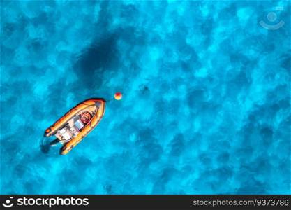 Aerial view of beautiful orange boat in blue sea at sunset in summer. Sardinia, Italy. Top drone view of motorboat, ocean with transparent azure water. Travel. Tropical scenery. Yachting. Seascape