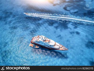 Aerial view of beautiful red luxury yacht and boat in blue sea at sunset in summer. Sardinia island, Italy. Top view of speed boat, sea coast, transparent water. Travel. Tropical landscape. Yachting 